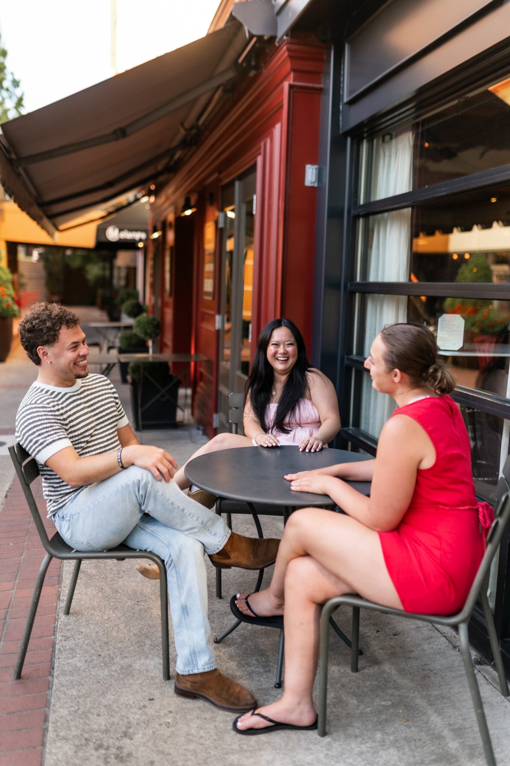 Three friends sitting on a sidewalk table outside a restaurant in Eugene, Oregon