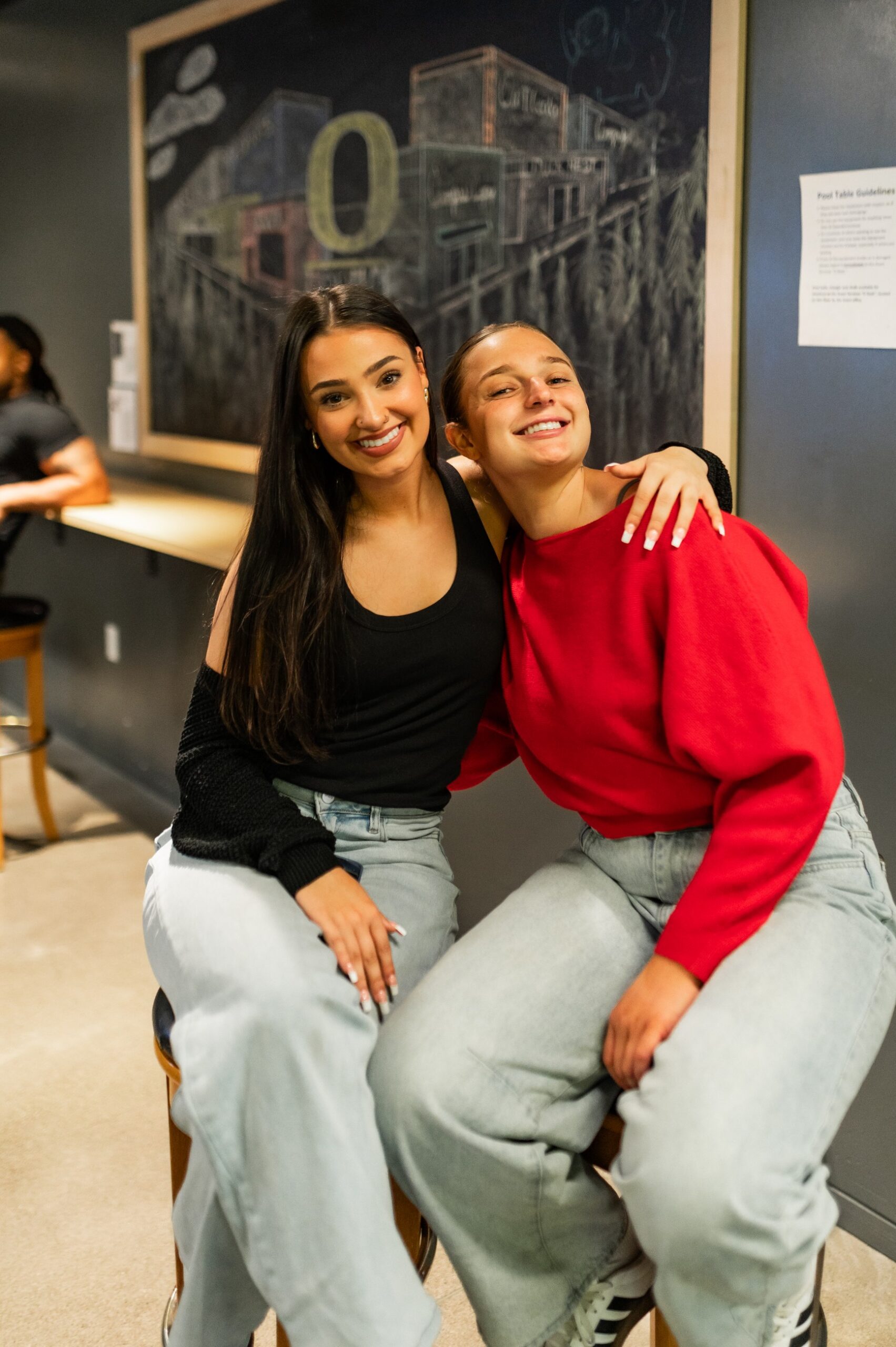Two friends posing for a photo in the basement of the EMU at the University of Oregon