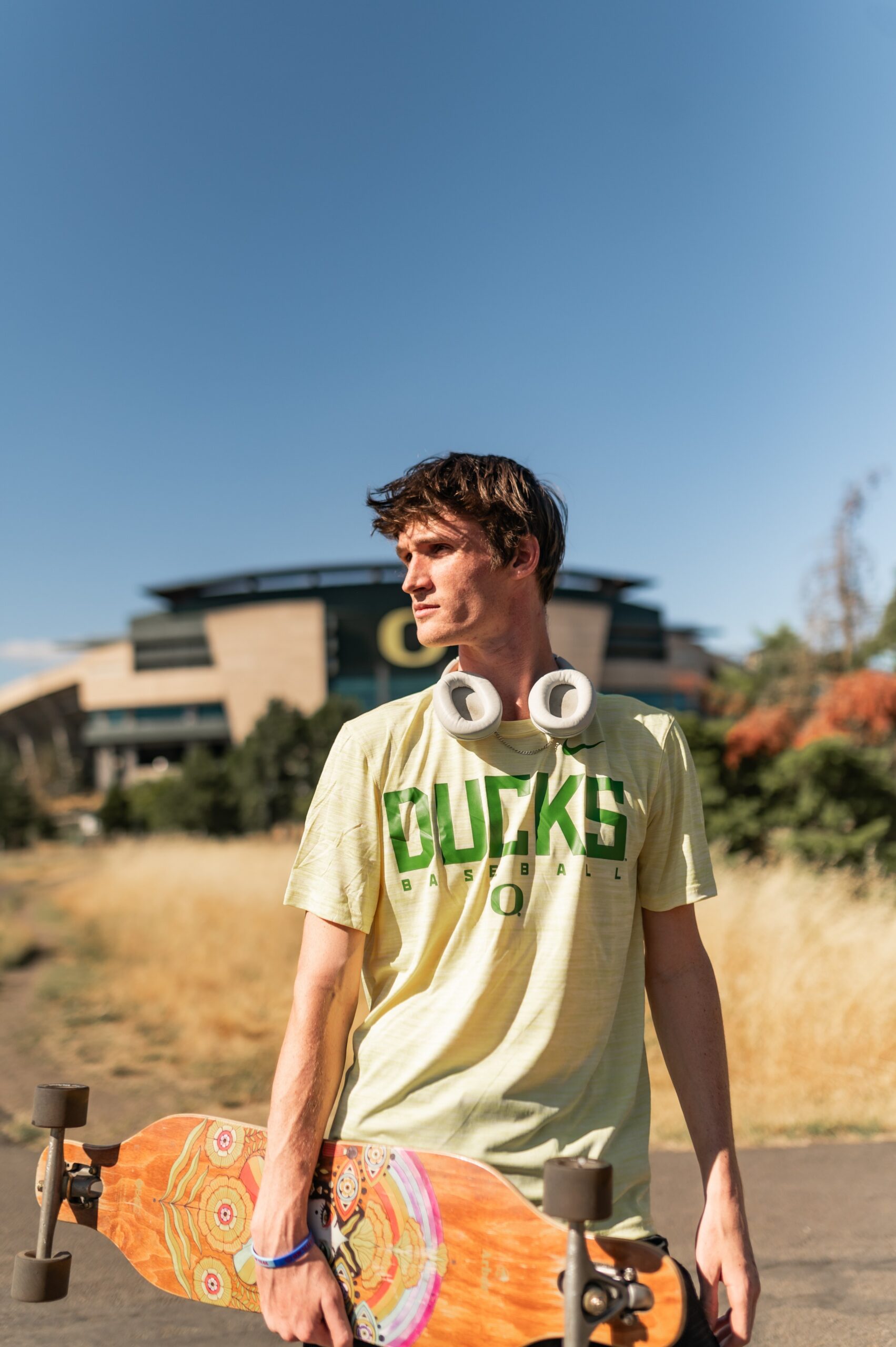 Young man walking back from Autzen Stadium with his long board