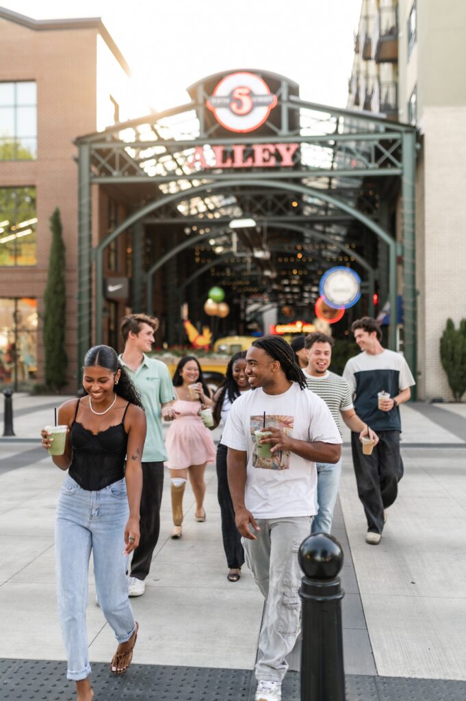 A group of college students walking outdoors near 5th Street Alley holding cold iced drinks