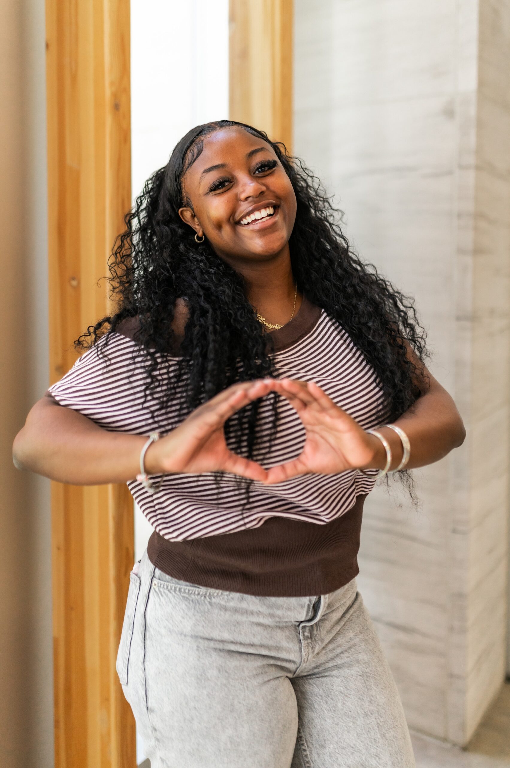 A smiling female student making the 22Go Ducks22 hand gesture inside a campus building scaled